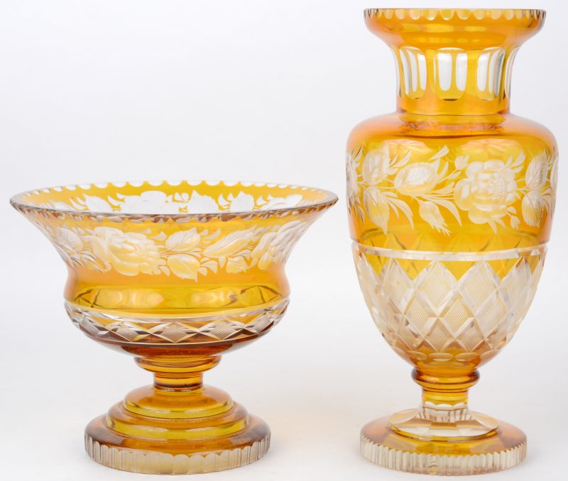 Een coupe op voet en een vaas van geslepen amberkleurig en kleurloos glas, versierd met een bloemendecor.