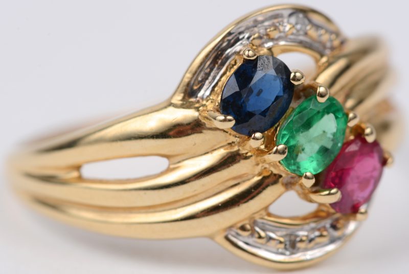 Een 18 karaats geel gouden ring bezet met twee kleine diamantjes en met saffier, smaragd en robijn met een gezamenlijk gewicht van 0,30 ct.
