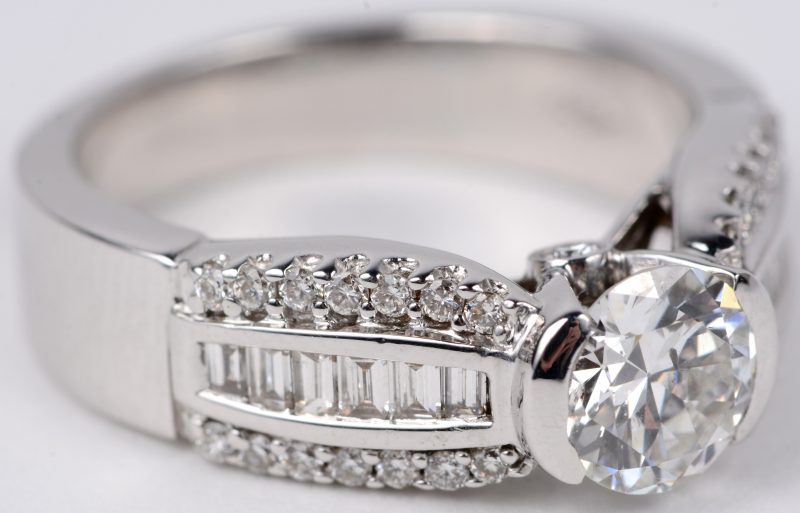 Een 18 karaats wit gouden ring bezet met een centrale diamant van ± 0,80 ct. en diamanten en baguetten met een gezamenlijk gewicht van ± 0,80 ct.