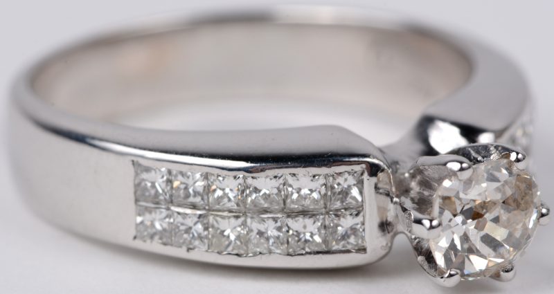Een 18 karaats wit gouden ring bezet met een centrale diamand van ± 0,80 ct. en diamant princessen met een gezamenlijk gewicht van ± 1,20 ct.