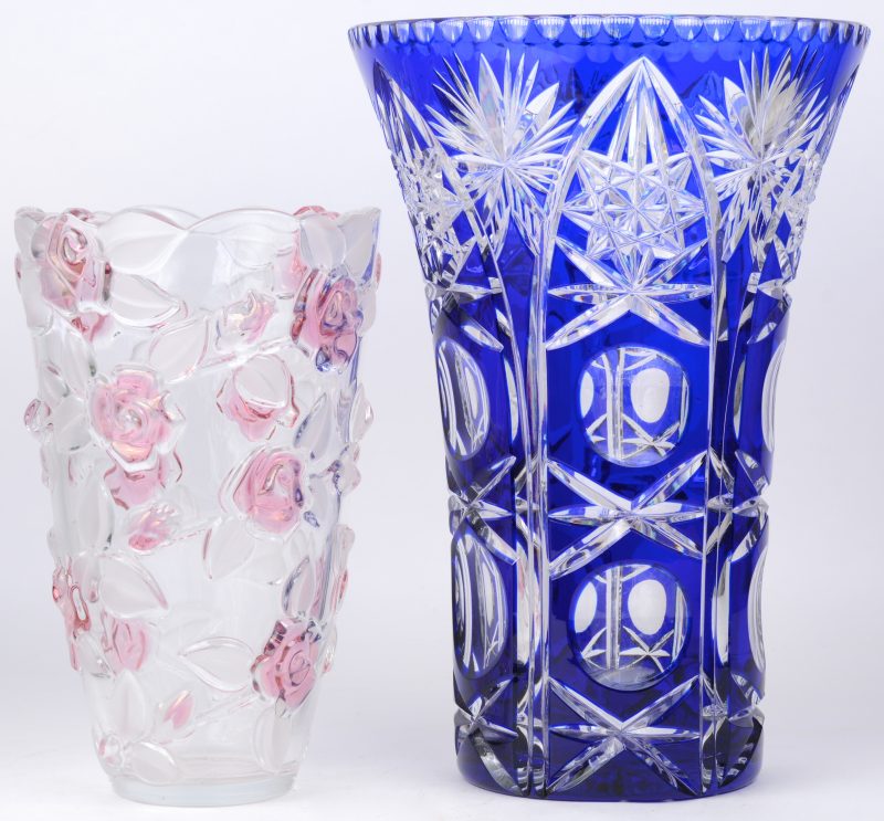 Een vaas van geslepen Boheems kristal, blauw gekleurd in de massa. We voegen er een kleurloze glazen vaas, versierd met roze en gesatineerde roosjes.