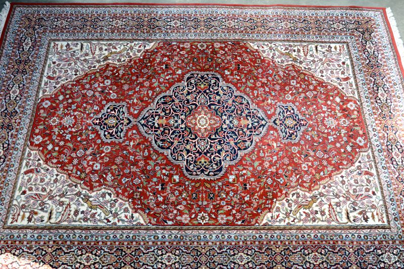 Een handgeknoopt Oosters wollen tapijt met een centraal medaillon.