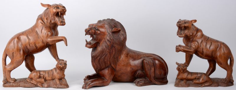 Drie beelden van gesculpteerd hout, waarbij twee in de vorm van een leeuwin met een welp en één in de vorm van een liggende leeuw. Eén oortje beschadigd.