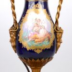 Een paar vazen van Sèvresporselein met hendgeschilderde classicistische decors in cartouches op kobaltblauwe fond. Met verguld bronzen monturen en voet. XIXe eeuw. De decors gesigneerd. Gemerkt en genummerd. Gemonteerd als lampen.