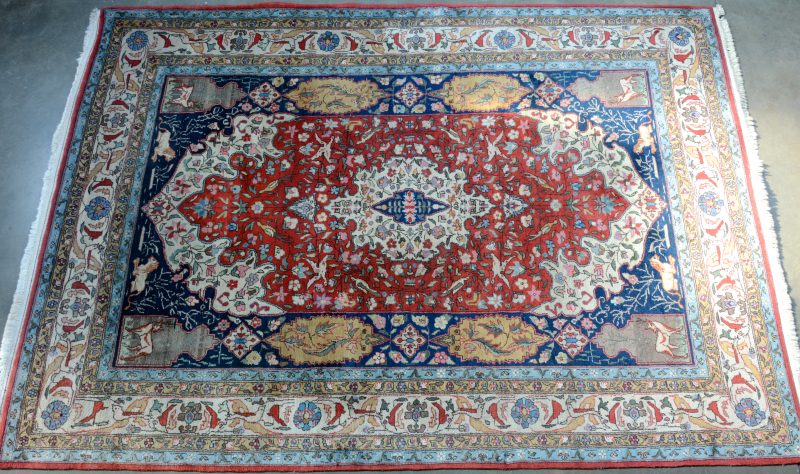 Een handgenoopt Perzisch wollen tapijt met een centraal medaillon en dieren.