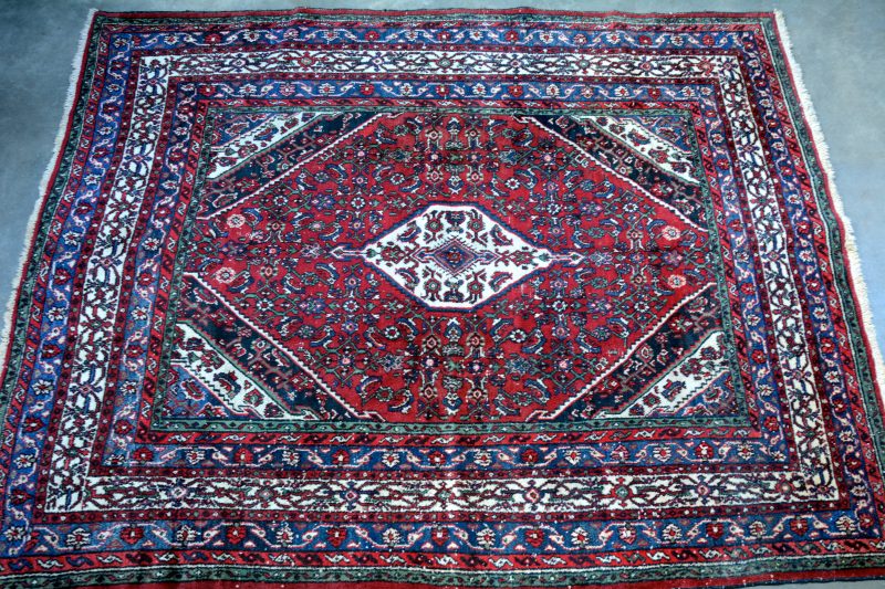 Een antiek handgeknoopt Perzisch wolen tapijt.