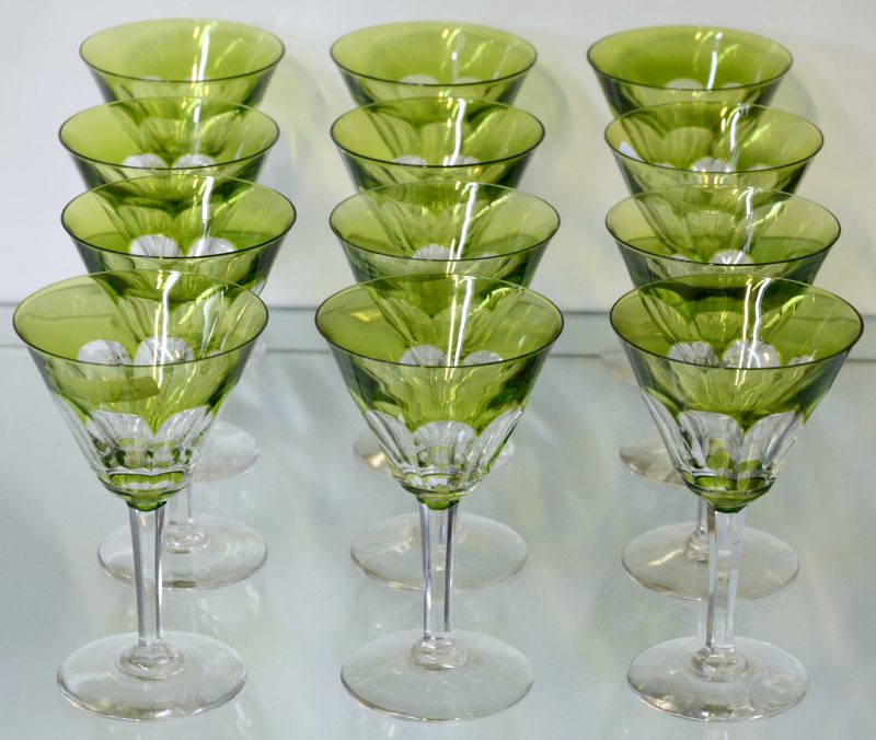 Een reeks van twaalf glazen van kleurloos en groen kristal.