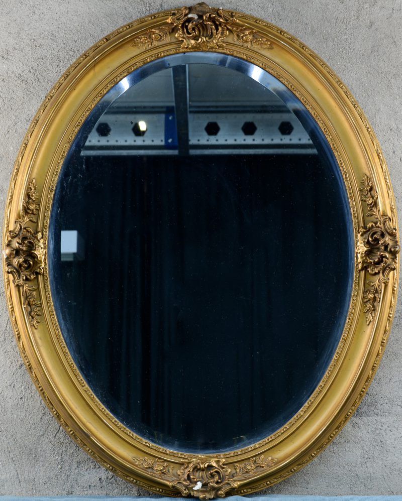 Een ovale spiegel in verguld houten lijst in Lodewijk XV-stijl.