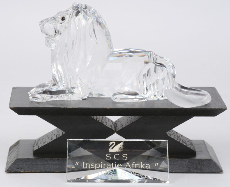 “De leeuw”. Een kristallen object uit de reeks “Inspiratie Afrika” naar ontwerp van Adi Stocker. Jaarlijks item 1995. In originele verpakking en met display. We voegen er een plaquette met opschrift “Inspiratie Afrika 1993 - 1995” aan toe.