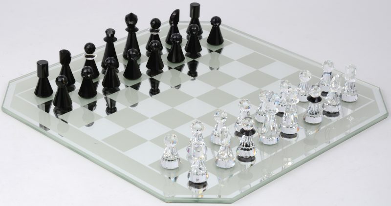 Een schaakspel uit de reeks “Silver Crystal” met zwarte en kleurloze stukken op een spiegelend speelbord en in originele doos.