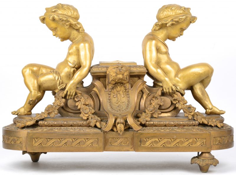 Een basis van een verguld bronzen klokstel, versierd met twee zittende putti. Twee pootjes en de pendule manco.
