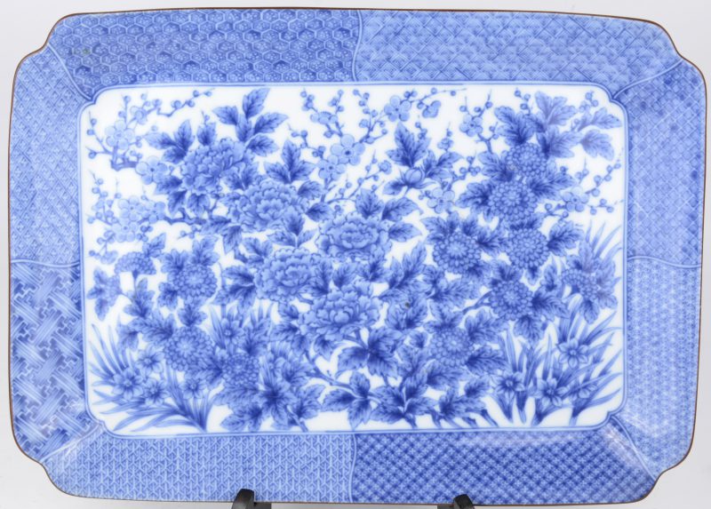 Een rechthoekige schotel van Chinees porseein met een blauw en wit decor van pioenen. Onderaan gemerkt.