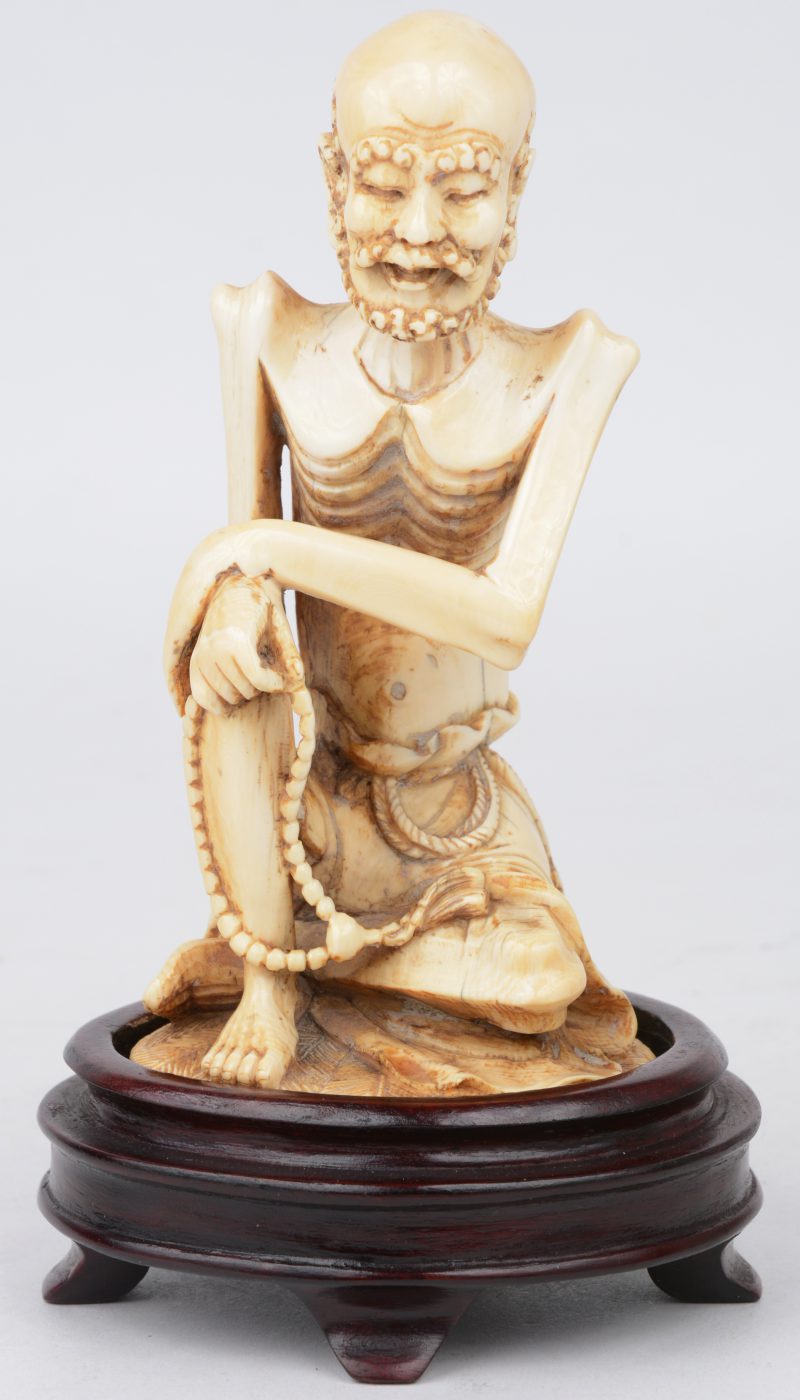 “Oude wijze”. Een beeldje van gesculpteerd Chinees ivoor op een houten voetstukje.