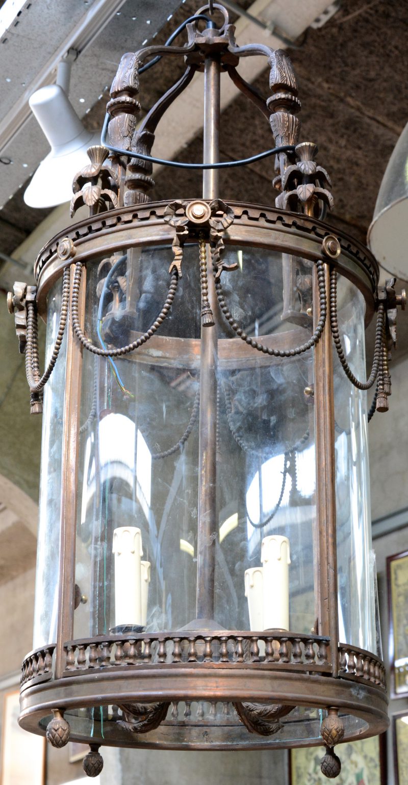 Een hanglantaarn van brons en glas in Lodewijk XVI-stijl.