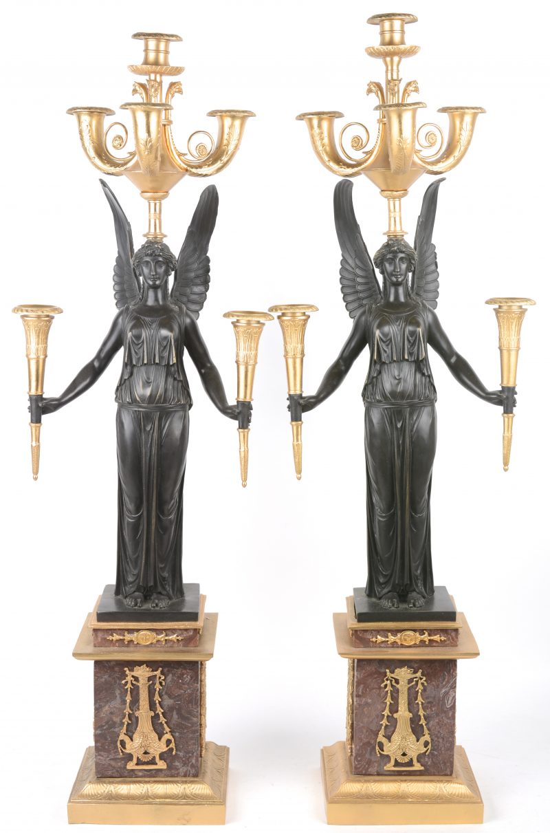 Een paar vergulde kandelaars in empirestijl, gedragen door bronzen engelen en op marmeren voetstukken, versierd met verguld brons.
