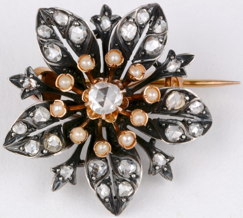 Een 18 karaats geel gouden en zilveren bloemvormige Victoriaanse broche bezet met diamanten oude slijp met een gezamenlijk gewicht van ± 1 ct. en pareltjes.