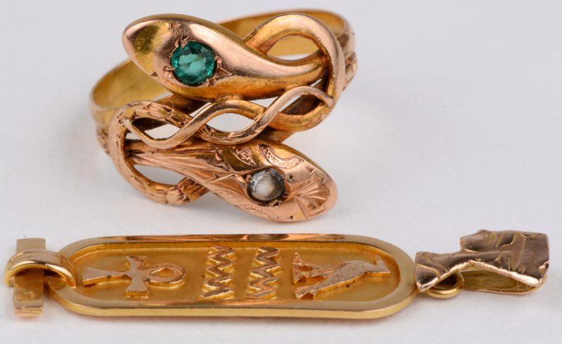 Een 18 karaats geel gouden ring in de vorm van slangen met fantasiestenen en een hanger met hierogliefen.