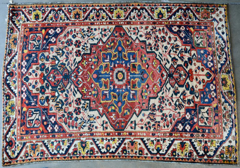Een handgeknoopt Perzisch wollen karpet met een centraal motief.