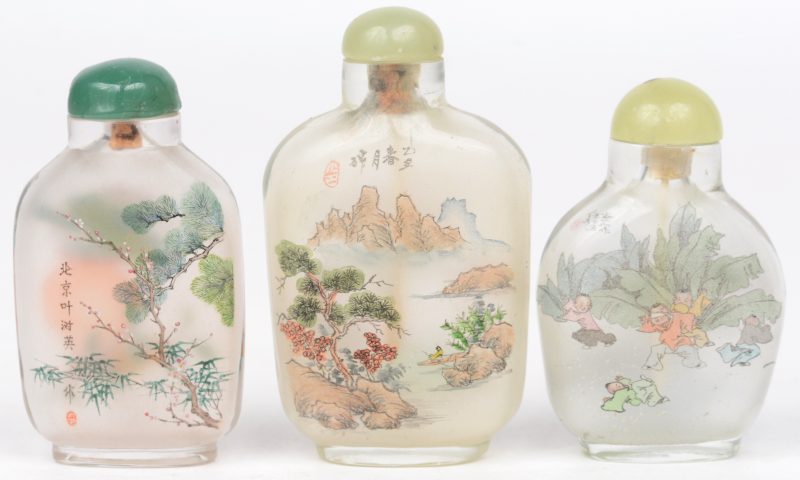 Drie Chinese glazen snuffbottles met verschillende decors. Allen gesigneerd.