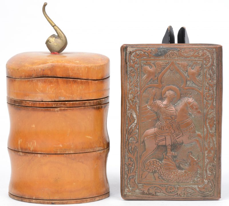 Een koperen icoon van St. Michel ‘de drakendoder.’ en een cilindervormige  tabakspot uit citroenhout gedecoreerd met een messingen pijp.