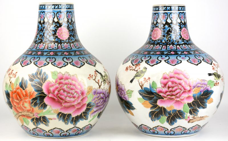 Een paar buikvazen van Chinees porselein met een meerkleurig decor van bloemen en vogels. Onderaan gemerkt en gedateerd 1982.