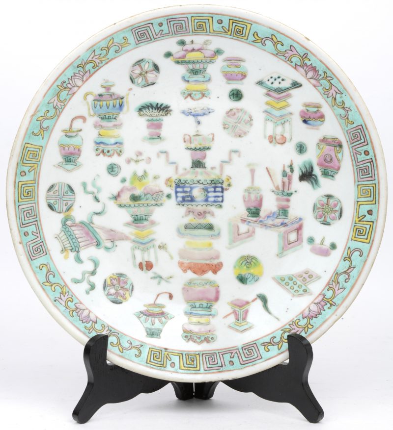 Een schotel van meerkleurig Chinees porselein met een decor van kostbaarheden.