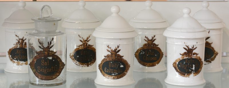 Een lot van zeven XIXe eeuwse apothekerspotten, waarbij zes van porselein en één van glas.
