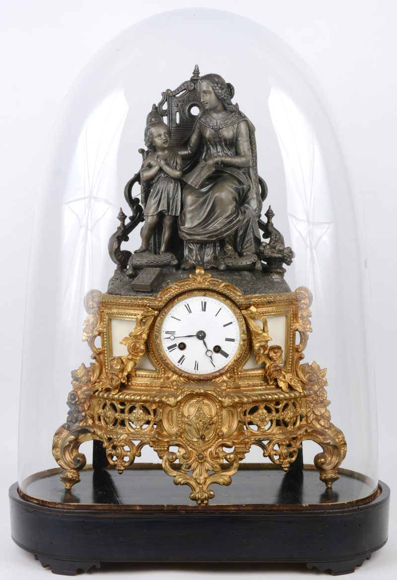 Een schouwpendule van verguld brons met een allegorische tinnen voorstelling bovenaan. Onder stolp.
