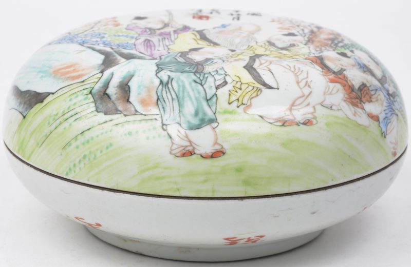 Een ronde zalfdoos van Chinees porselein met een meerkleurig decor van personages.