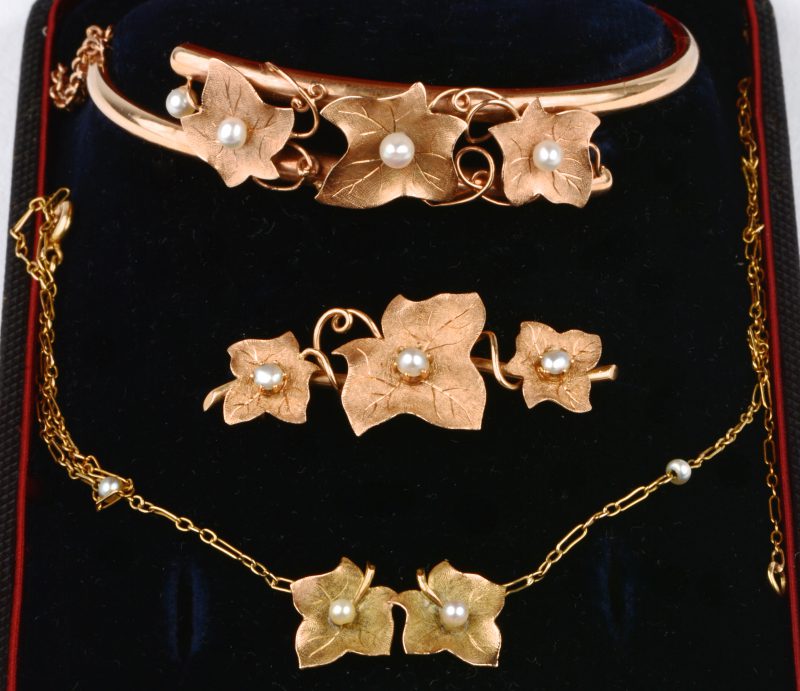 Een 18 karaats geel gouden armband, broche en ketting met hanger in blad vorm bezet met pareltjes. In etui.