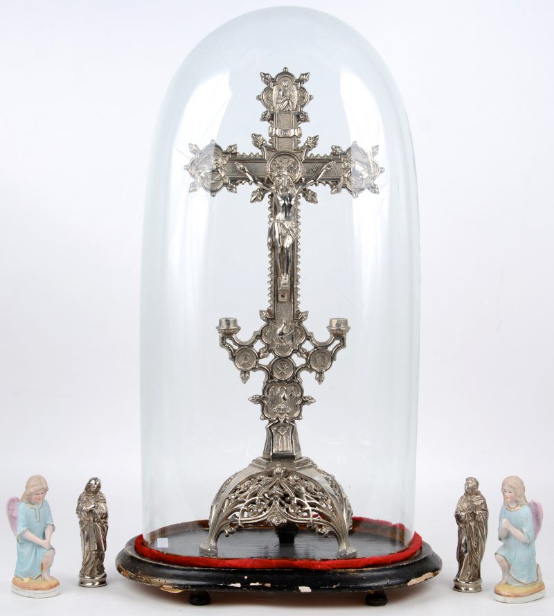 Een metalen kruisbeeld onder glazen stolp. Met twee kleine, losse heiligenbeeldjes.