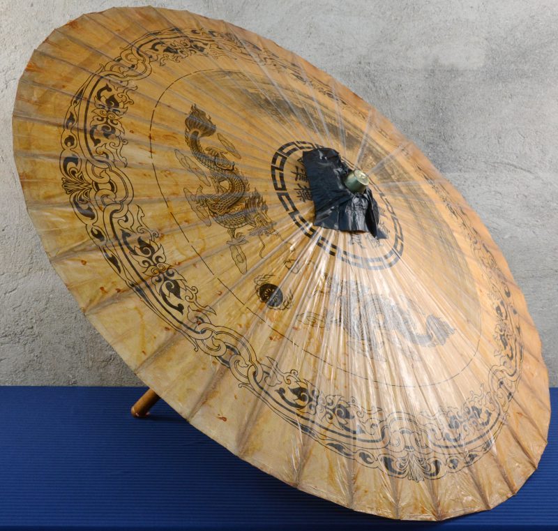 Een Chinese parasol van hout en papier met een decor van draken en een landschap.