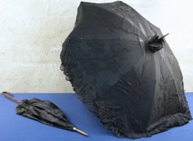 Twee antieke parasolletjes, waarbij één van zwarte kant en met een koperen handgreep, de andere van zwarte kant en borduursel. Omstreeks 1900.