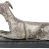Een liggende hond van brons op een houten voetstukje.