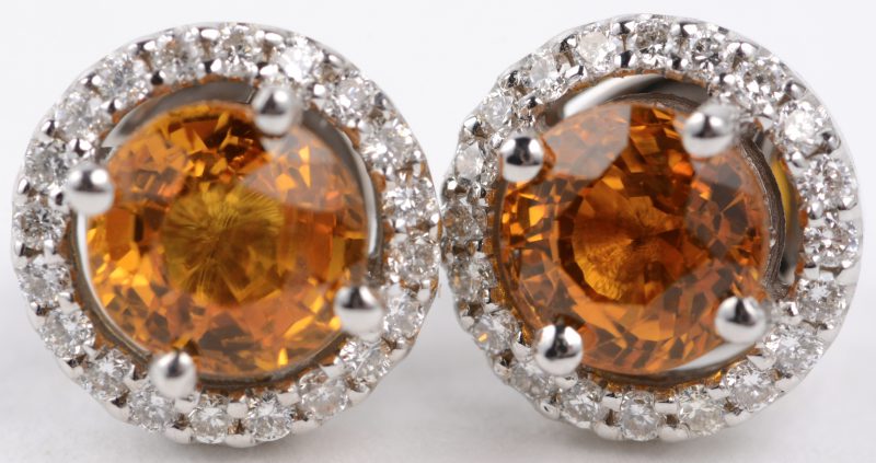 Een paar 18 karaats wit gouden oorbellen bezet met diamanten met een gezamenlijk gewicht van ± 0,38 ct. en twee gele saffieren met een gezamenlijk gewicht van ± 1,38 ct.