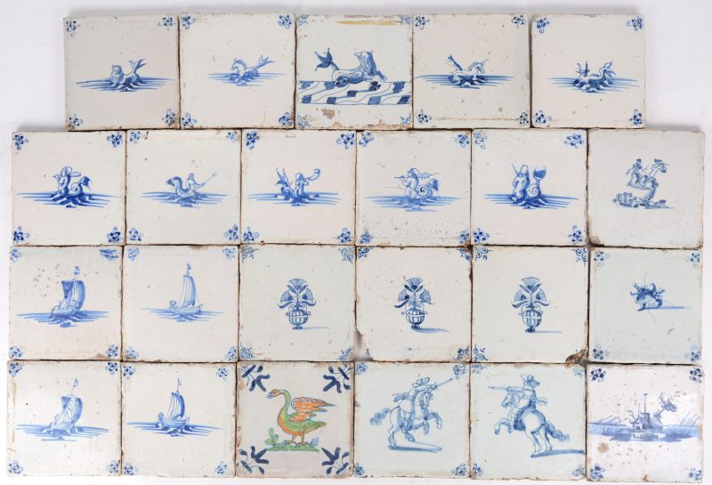 Een lot van 23 Delftse tegels met blauw en witte decors, één gepolychromeerd. XVIIIe en XIXe eeuw.