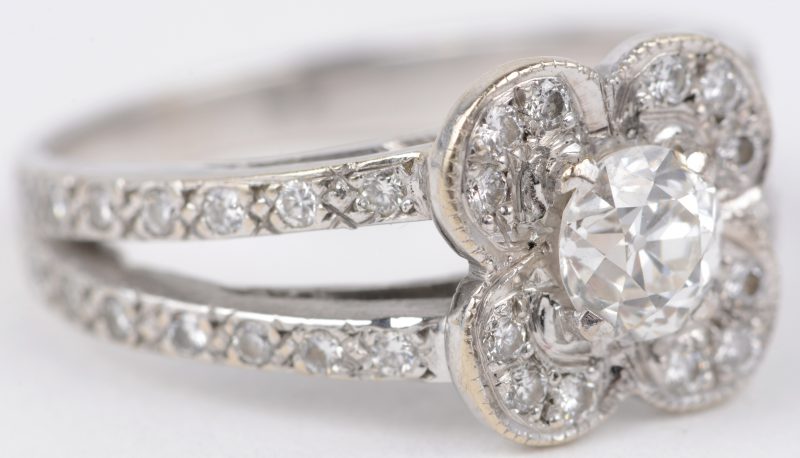Een 18 karaats wit gouden ring bezet met een centrale diamant van ± 0,60 ct. en diamanten met een gezamenlijk gewicht van ± 0,40 ct.
