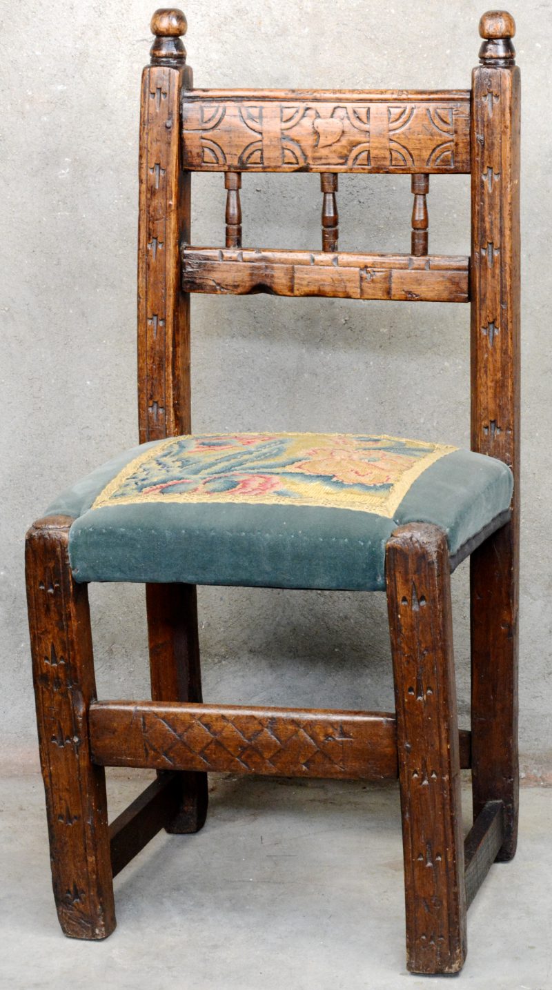 Een gebeeldhouwde eikenhouten stoel, met XVIIe eeuwse tapisserie in de bekleding.