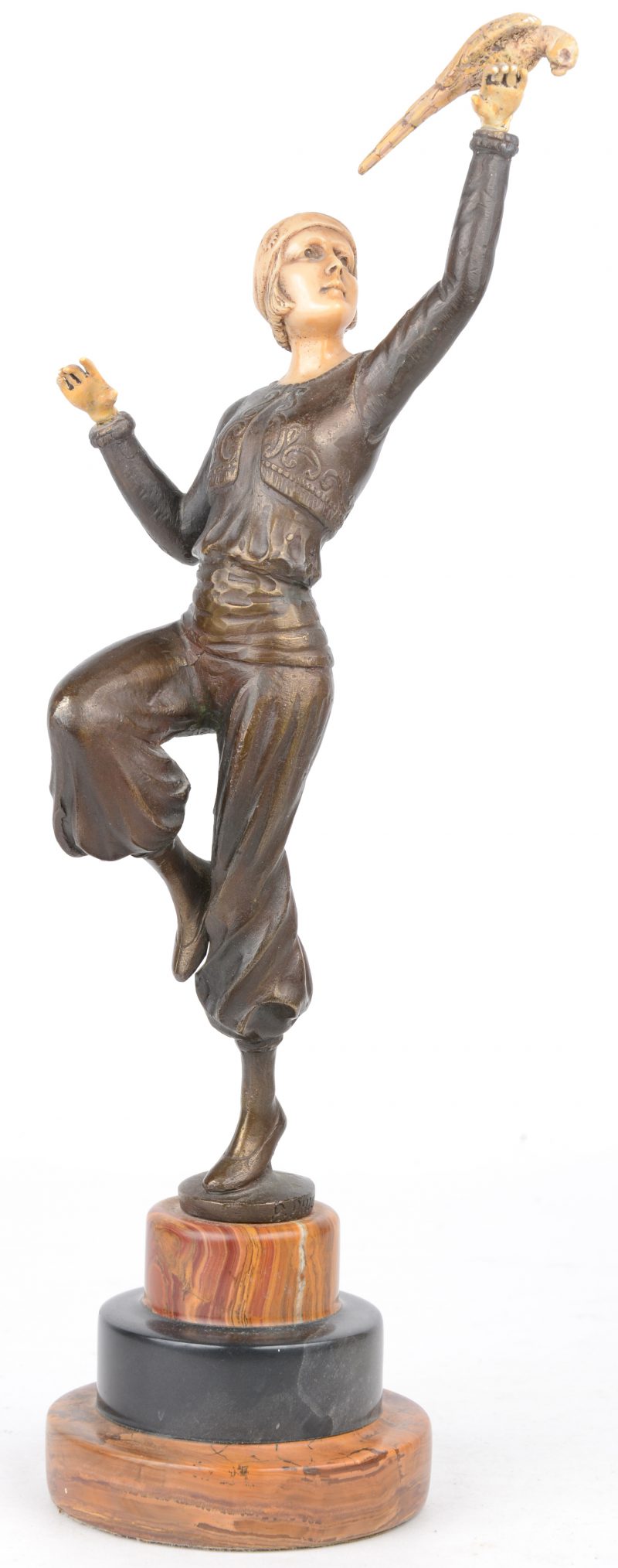 “Vrouw met vogel”. Een bronzen beeld met hoofd, handen en vogel van ivorine en op voetstuk van meersoortig marmer. Naar een werk van Paul Philippe.