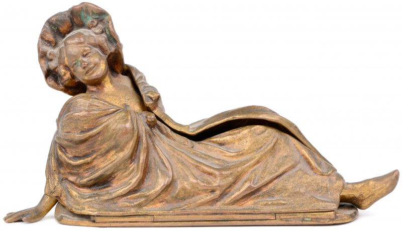 Een mechanisch bronsje in de vorm van een liggende vrouw met wegklapbare gewaden.