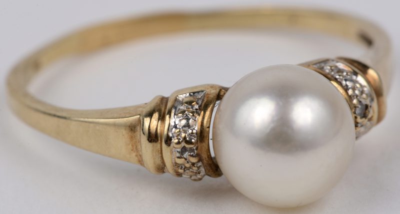 Een 14 karaats wit en geel gouden ring bezet met twee kleine diamantjes en  een parel.