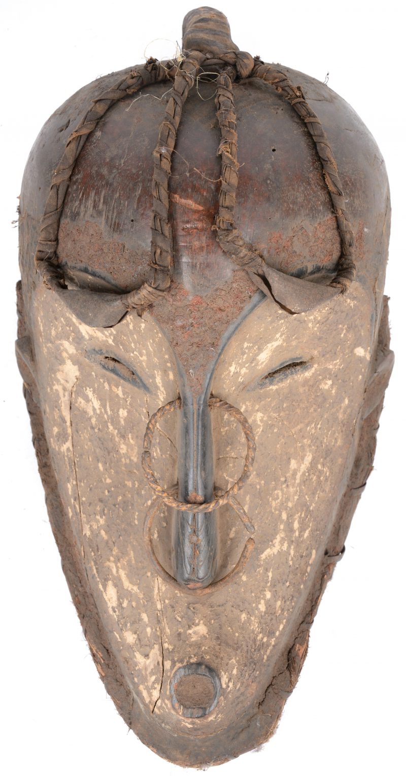 Een Afrikaans masker van gepolychromeerd hout, versierd met metalen ringen en belletjes.