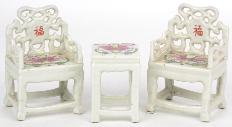 Een driedelig setje uit porselein waaronder twee stoeltjes en een tafeltje.