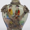 Een Chinese églomisé snuff bottle versierd met geschilderde dames en aan de buitenkant met draak en pauw. Onderaan gemerkt.