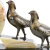 Een driedelig klokstel van onyx en zwart marmer, versierd met twee fazanten van zamak. Tijdperk art deco.