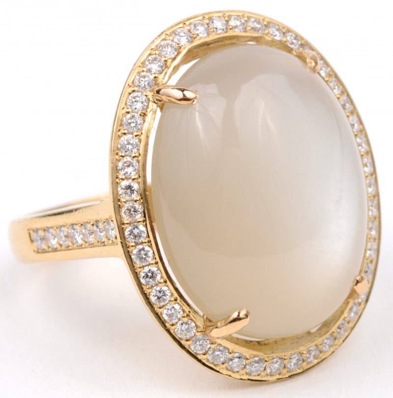 Een 18 karaats geel gouden ring bezet met diamanten met een gezamenlijk gewicht van ± 0,55 ct. en een centrale maansteen van ± 12,10 ct.