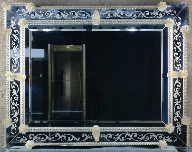 Een Venetiaanse spiegel met glazen versieringen en geslepen motieven.