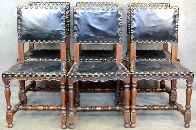 Een reeks van zes stoelen van gedraaid eikenhout met lederen bekleding.