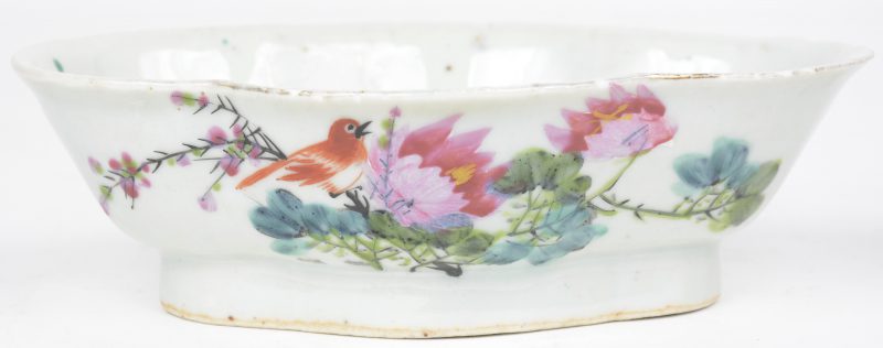 Een schaaltje van Chinees porselein met een meerkleurig decor van een vogel en bloemen. Schilfer.