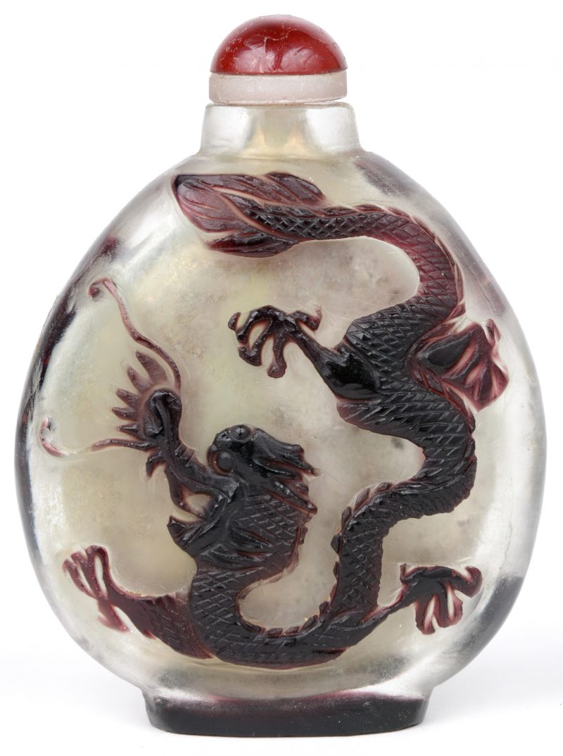 Een Chinese flacon van kleurloos glas met een bruin-paarse reliëfdecor van een draak en een mythische vogel. De stop van rood dennenhars. Omstreeks 1900.